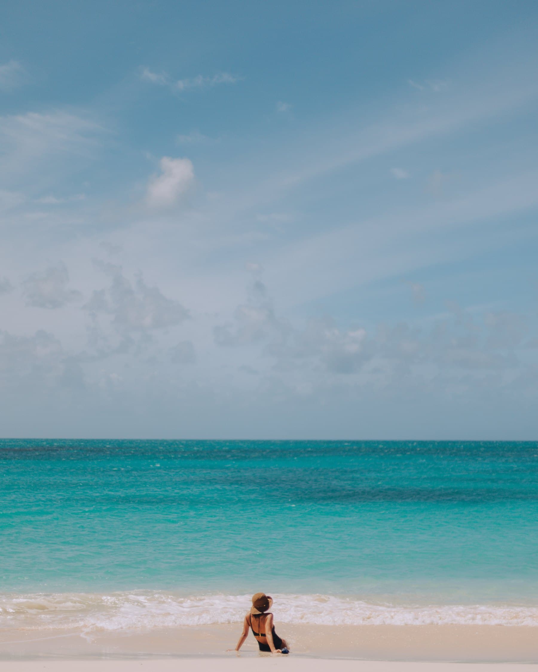 A lone swimmer at the water’s edge under a wide sky