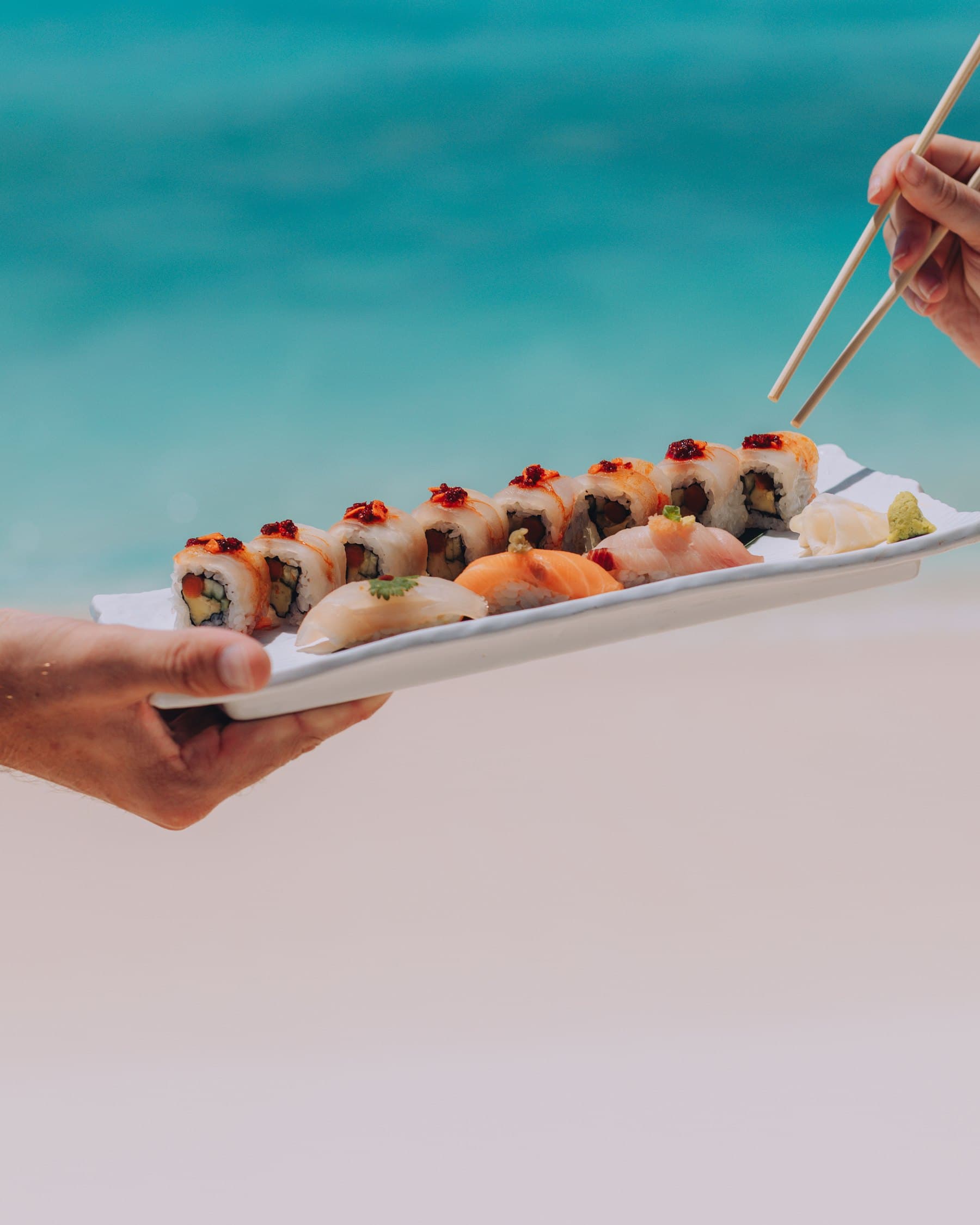 Sushi served on a long plate over white sand